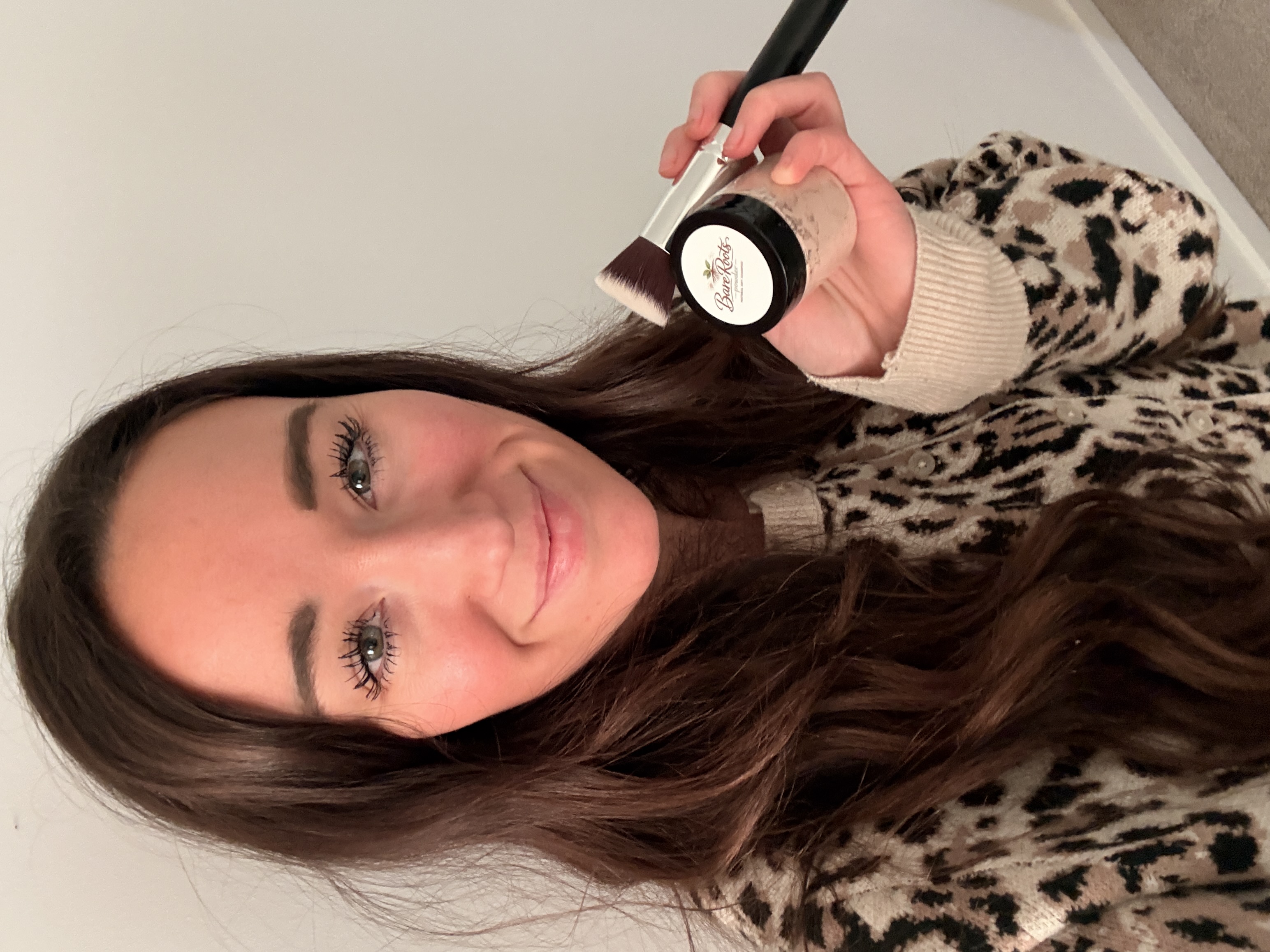 Product owner holding BareRoots Powder and application brush